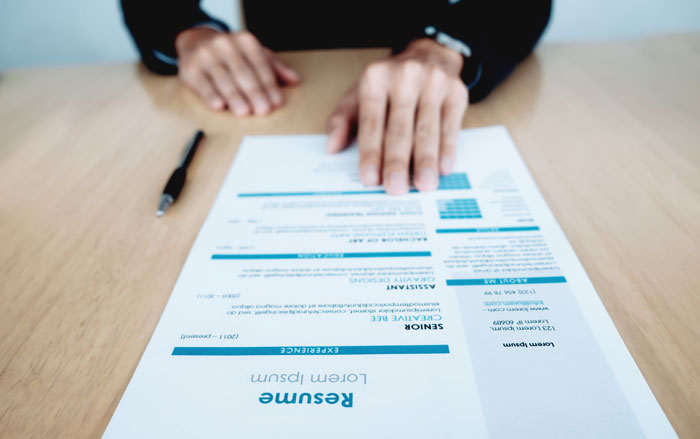 Person pointing at resume on desk, illustrating tense moment between employee and manager experiencing petty karma.