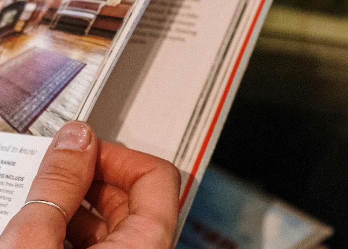 Close-up of a hand flipping through a magazine, illustrating signs related to the economy not doing well.