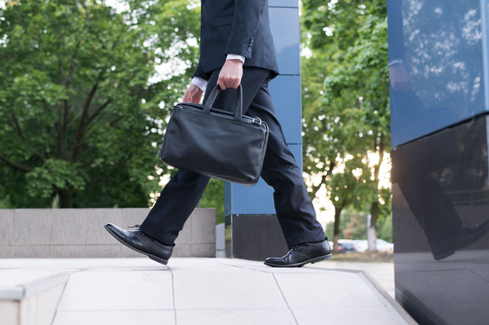 A business person strides forward with a briefcase. Representing satisfying revenge against toxic bosses.