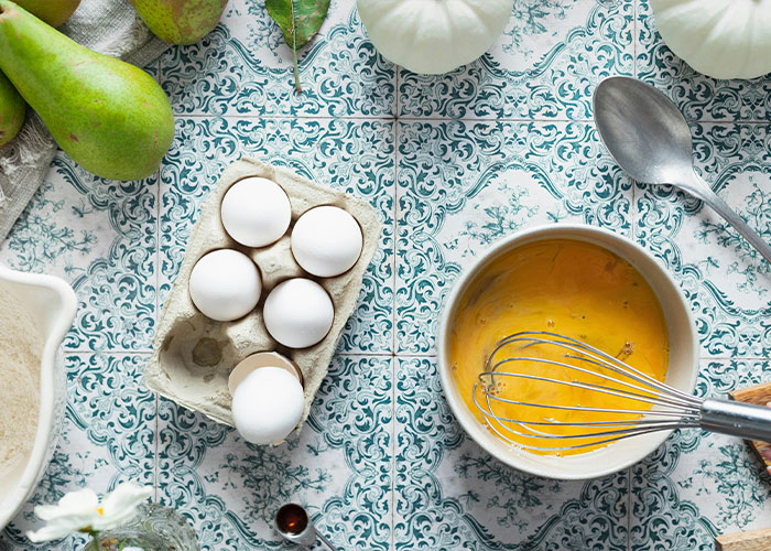 Foto aérea de ovos em uma caixa e uma tigela de ovos batidos, sugerindo o consumo de ovos para tratamento de Alzheimer.