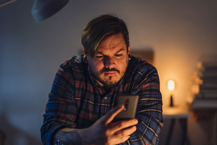 Man in a plaid shirt looking at phone with serious expression, reflecting teen confronts dad after forgetting birthday reaction Man in a plaid shirt looking at phone with serious expression, reflecting teen confronts dad after forgetting birthday reaction