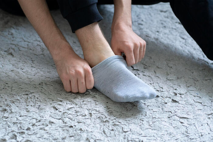 A person adjusts a light gray sock on their foot. A mundane moment after experiences medical workers wish they could unsee.