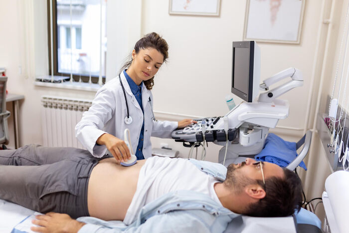 Female doctor using ultrasound device on male patient’s abdomen during a medical exam revealing random body facts.