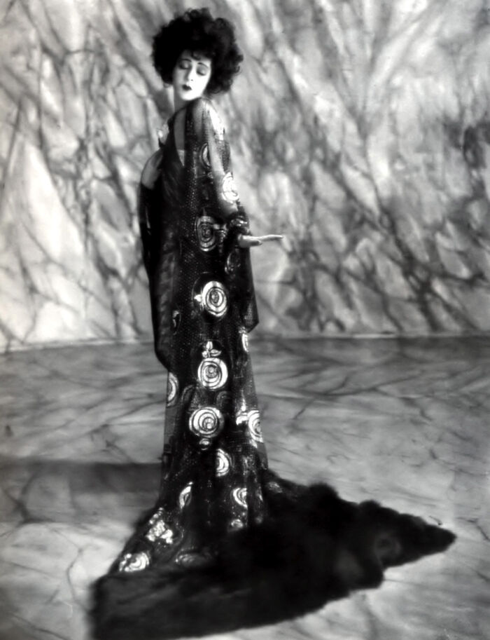 Vintage black and white photo of a woman in an elaborate gown, a rare and interesting moment from a past era.