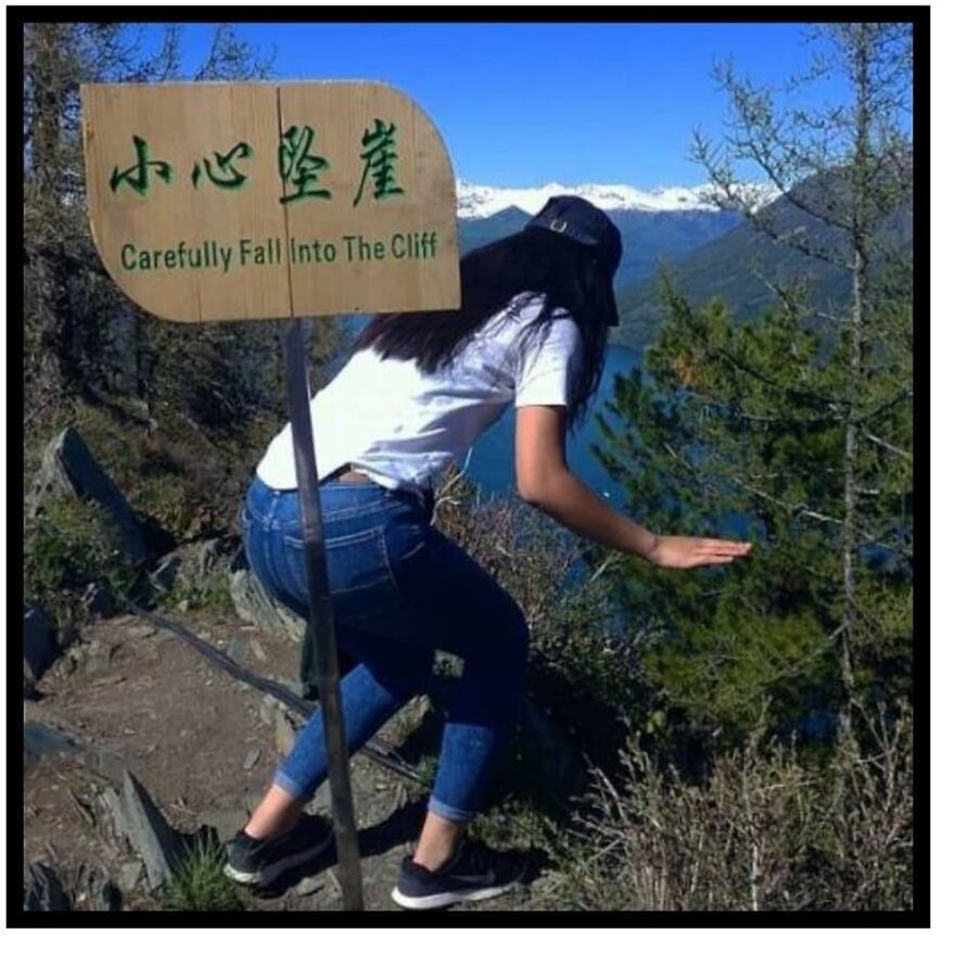 Woman near a cliff edge with a warning sign, illustrating a funny camping and hiking meme in a mountain setting.