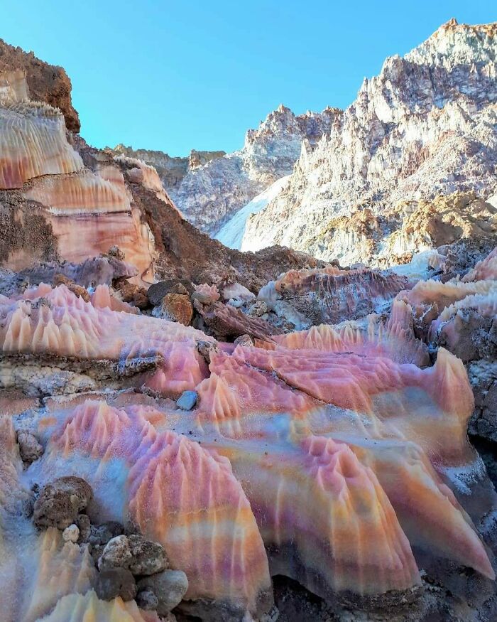 Unbelievable photos of colorful, layered rock formations under a clear blue sky, resembling another universe on Earth.