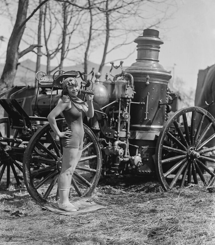 Woman in vintage swimwear posing next to an old steam-powered vehicle in rare and interesting photos from the past.