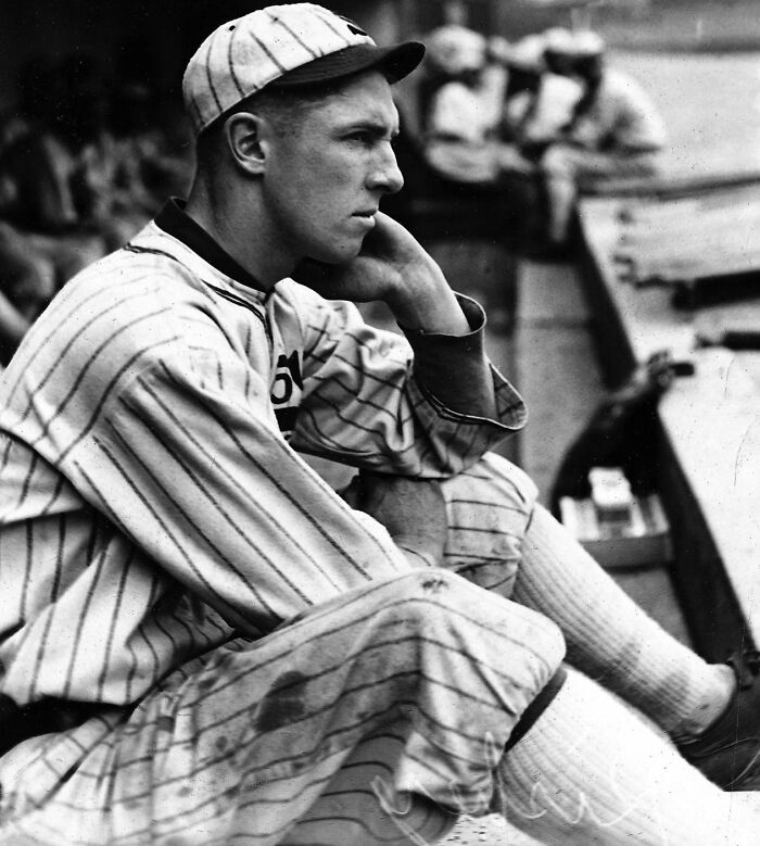Black and white photo of a vintage baseball player in uniform sitting thoughtfully on the bench, rare and interesting photo.