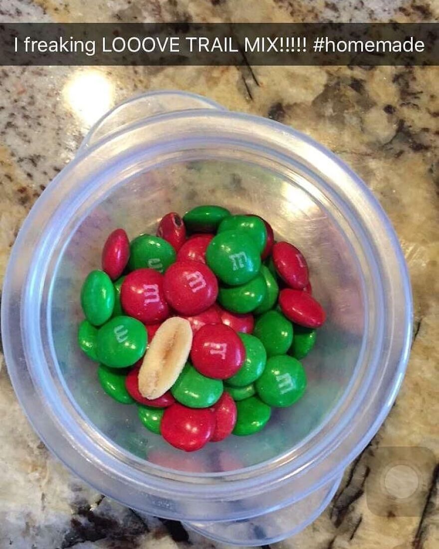 Small container with homemade trail mix of red and green candy-coated chocolates with a single peanut inside for camping and hiking.
