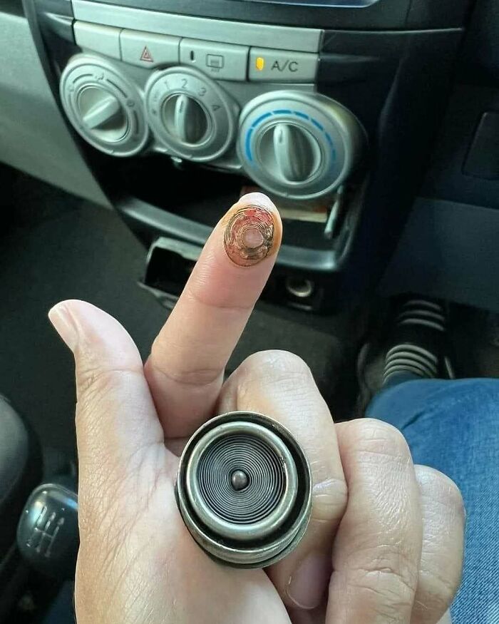Close-up of a finger with a removed car cigarette lighter coil, evoking '90s nostalgia memes and vintage car accessories.