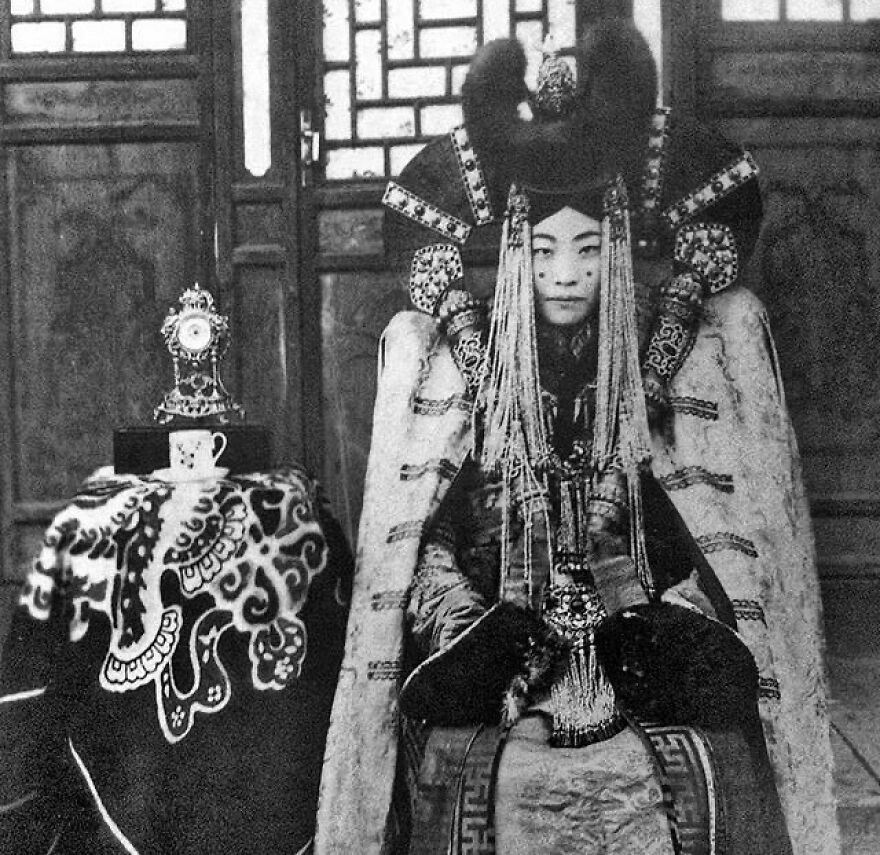 Fascinating photos teach about history: Mongolian queen in elaborate traditional attire, seated with a small decorative clock and cup.