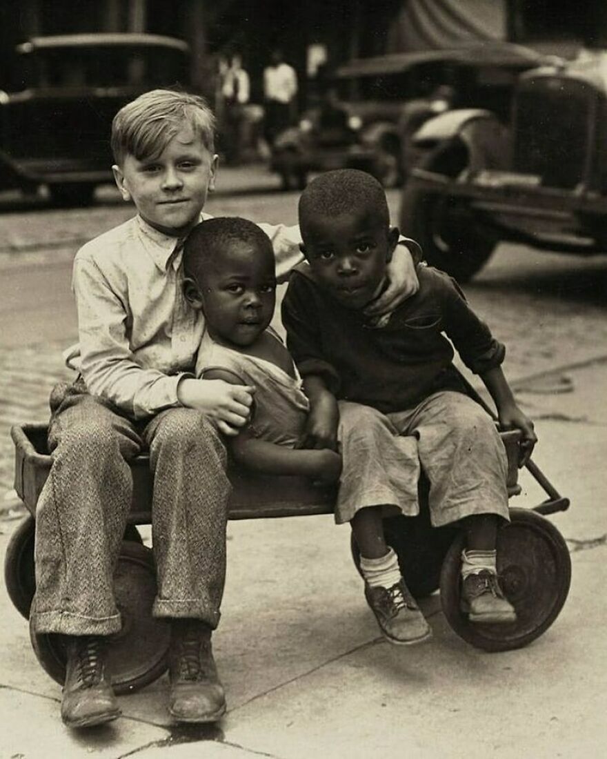 Three boys sit in a wagon, two younger Black children with an older white boy, a fascinating photo for history.