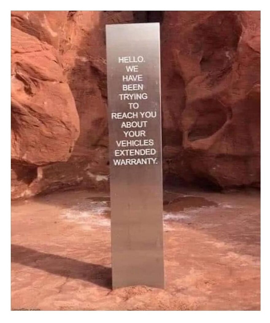 Metal monolith in red rocky terrain with humorous text about vehicle extended warranty, related to camping and hiking memes.