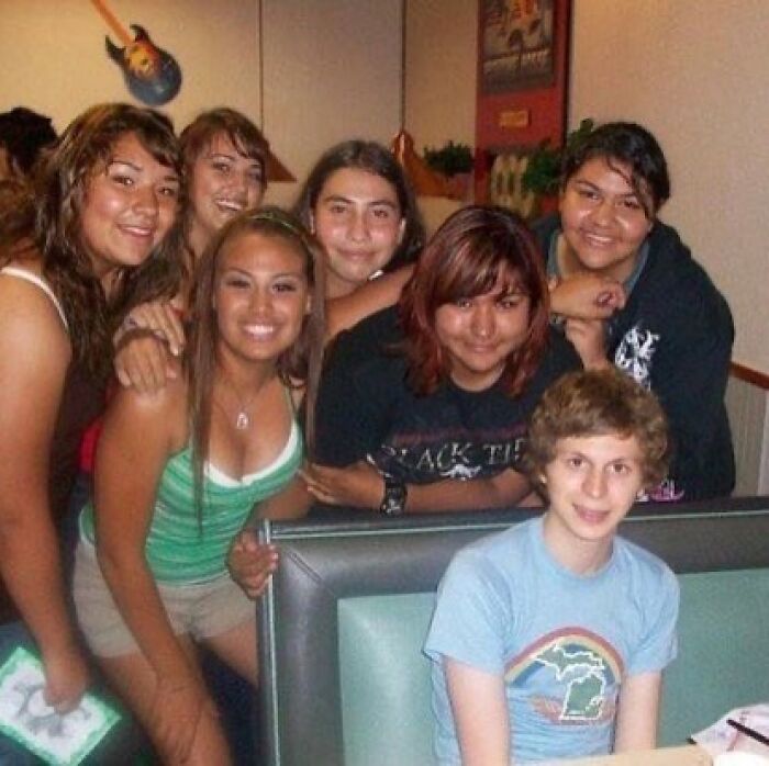 A cursed image showing Michael Cera with a group of smiling girls, looking confused, creepy, and amusing.
