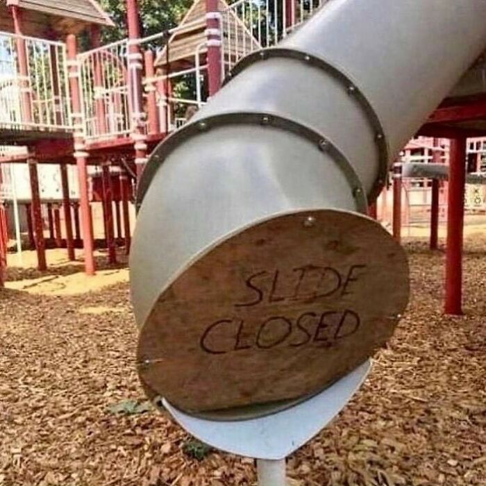 A playground slide is blocked off by a wooden board that says SLIDE CLOSED, making for a cursed image.
