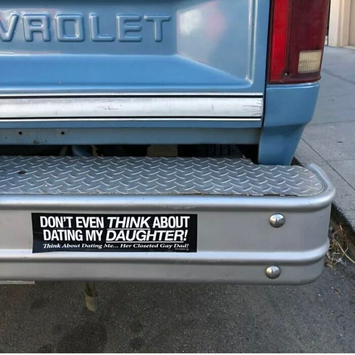 A cursed image of a humorous bumper sticker on a blue Chevrolet truck: "Don't even think about dating my daughter! Think about dating me... Her closeted gay dad!"