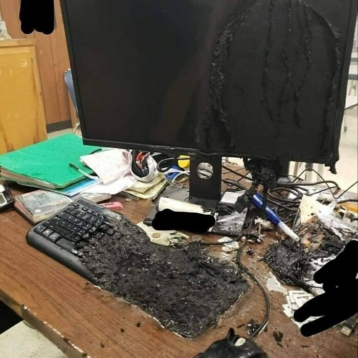 A melted keyboard and computer monitor covered in a black, tar-like substance, an image that confuses and creeps.