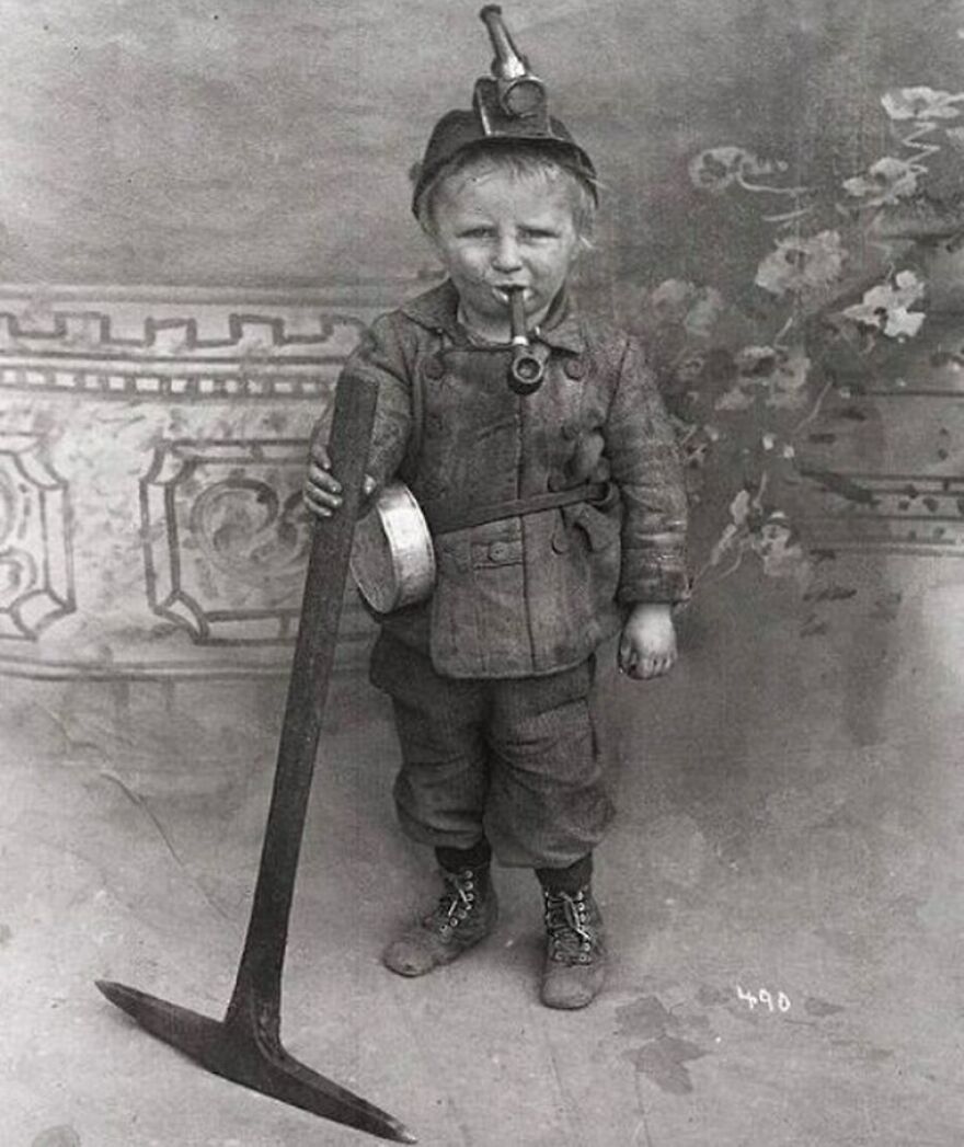 Fascinating photo of a young child dressed as a miner with a pickaxe and pipe, offering a glimpse into history.