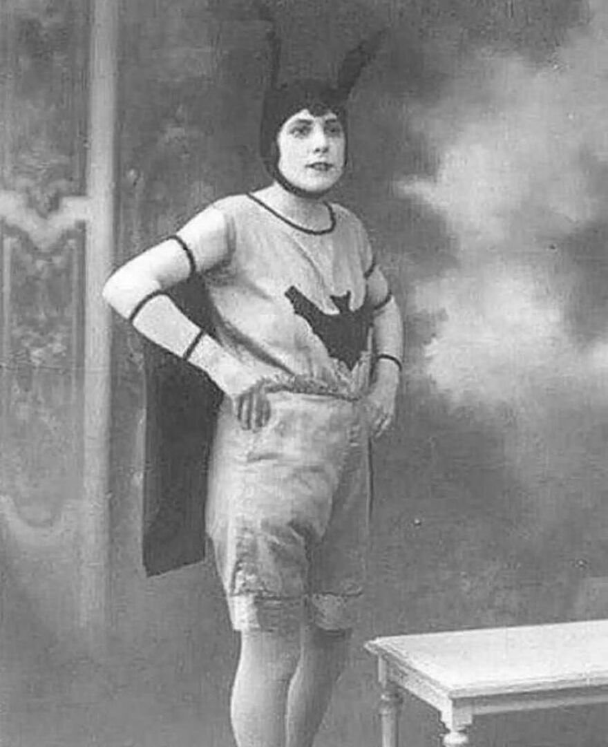 A woman in a bat-themed costume, posing in an old black and white photo, offering fascinating photos of history.