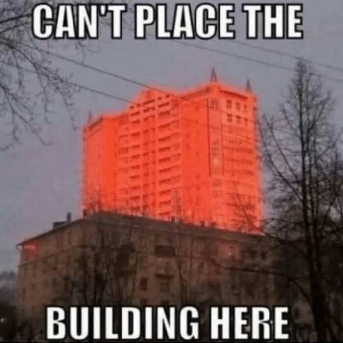 A cursed image of a large, glowing red building seemingly clipping through a smaller, older one with meme text.