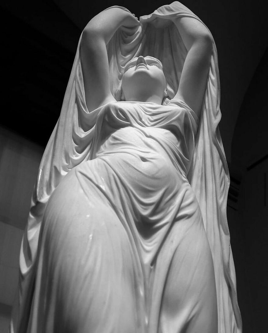 Dramatic black and white photo of a neoclassical marble statue, a woman shrouded in flowing fabric, adding to fascinating photos of history.