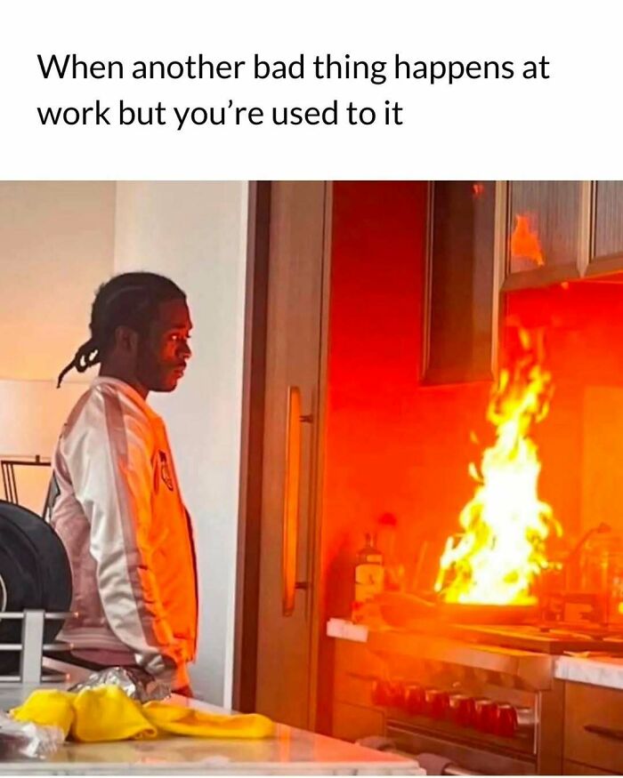 Man staring calmly at kitchen fire, illustrating relatable memes about the challenges of adulthood and work struggles.