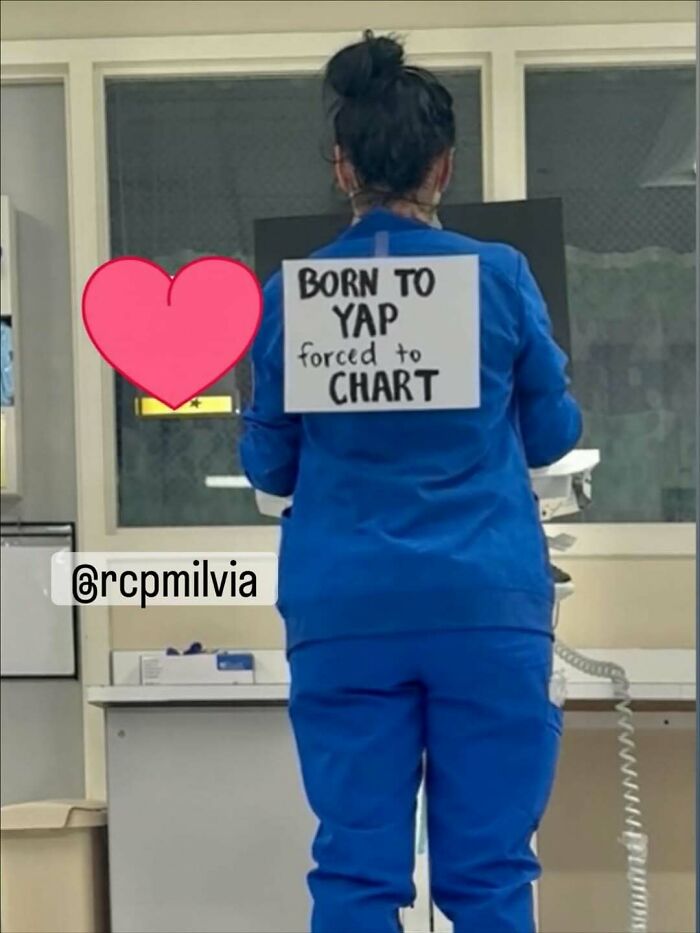 A nurse in blue scrubs faces away, wearing a sign: BORN TO YAP, FORCED TO CHART. A relatable nurse meme.