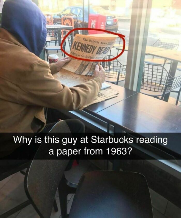 A man in a blue hoodie reads an old newspaper with a Kennedy D**d headline at Starbucks. Unhinged pic that makes no sense but is hilarious.