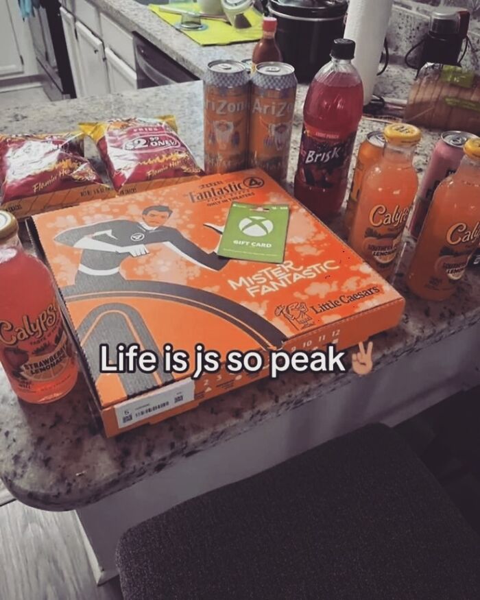 An unhinged pic of snacks, drinks, a pizza box with Mister Fantastic, and an Xbox gift card. Hilarious and makes no sense.