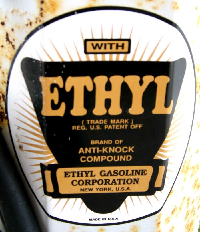 Close-up of a vintage Ethyl Gasoline Corporation label showing an anti-knock compound on a rusty surface.