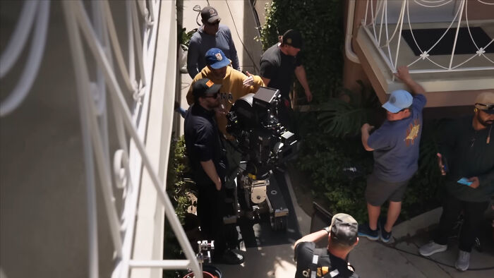 Vídeo BTS de Sydney Sweeney e a equipe do Euphoria filmando ao ar livre, com membros da equipe e equipamentos visíveis.