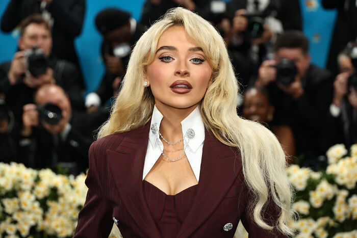 Blonde woman in a stylish maroon suit, white shirt with embellished collar, perfect for the Met Gala 2026.