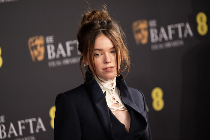 Supergirl star Milly Alcock poses in a dark outfit at the BAFTA awards, bracing for backlash while simply existing.