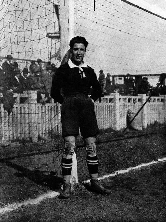 Vintage black and white photo of a soccer goalkeeper standing by the goalpost in a rare and interesting moment.