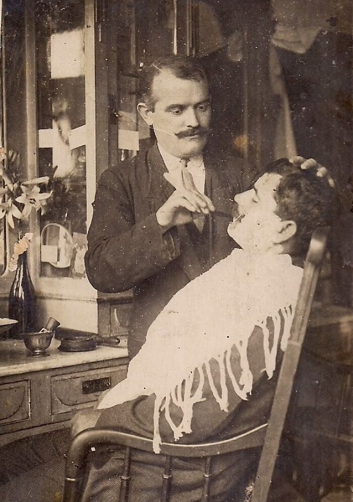 Vintage photo of a barber shaving a customer, showcasing rare and interesting moments from a time we cannot experience today.