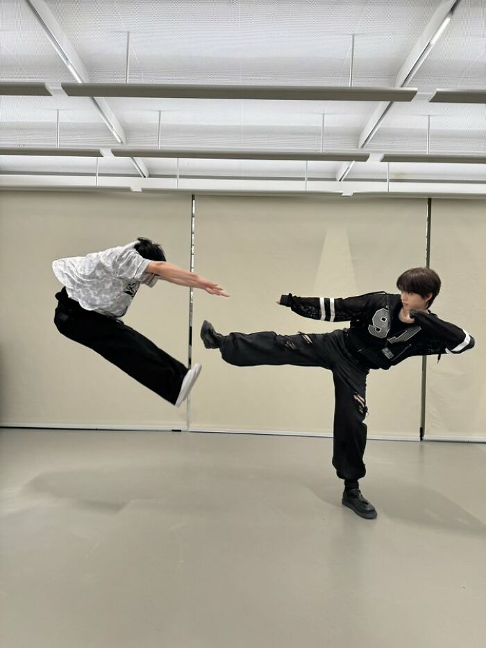 Two people pulling off a creative pose with one person mid-air and the other delivering a high kick indoors.