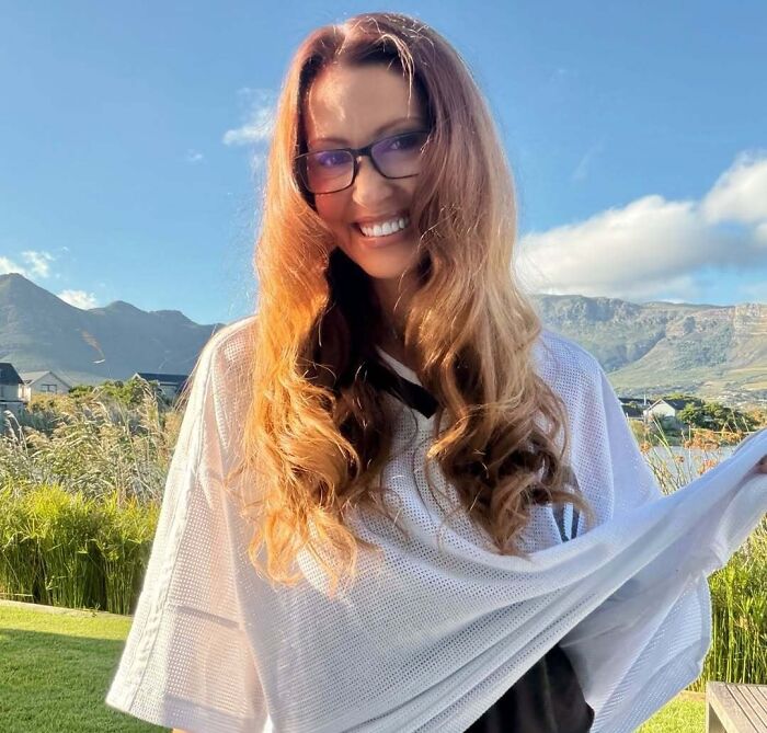 Mulher sorridente com longos cabelos ruivos e óculos ao ar livre, montanhas ao fundo. A geração do milênio está investindo milhões em sua paixão de infância.