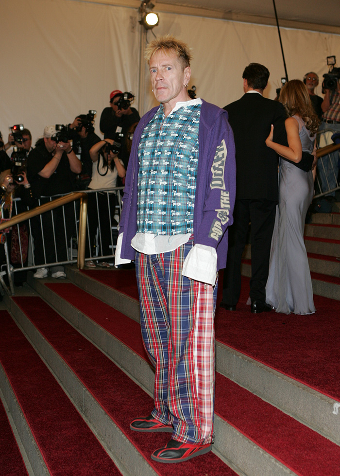 John Lydon in plaid pajamas and a purple hoodie, on a red carpet. A celebrity who hated the Met Gala.