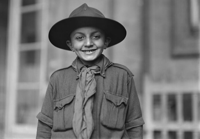 Boy scout smiling in vintage uniform wearing a wide-brimmed hat in rare and interesting photos from history.