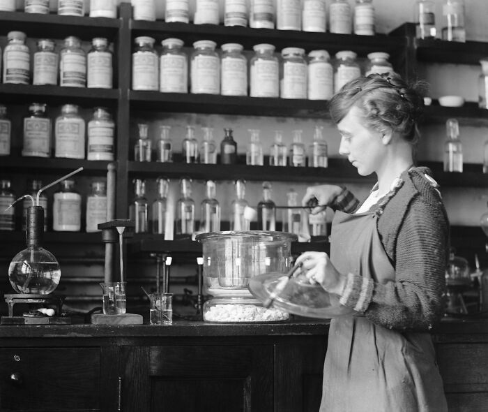 Woman in vintage laboratory preparing chemical experiment among jars and glassware in rare and interesting photos.