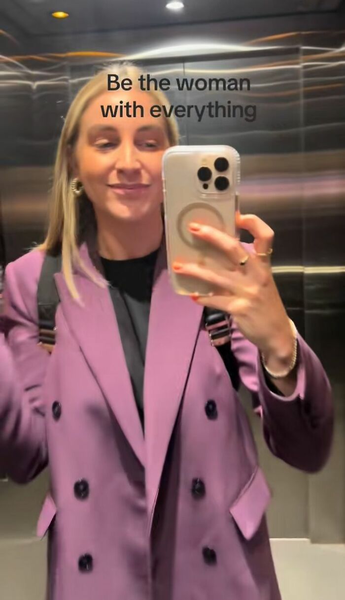 Mulher tirando uma selfie no elevador vestindo uma jaqueta roxa, ilustrando um sintoma bizarro de gravidez compartilhado online. Mulher tirando uma selfie no elevador vestindo uma jaqueta roxa, ilustrando um sintoma bizarro de gravidez compartilhado online.