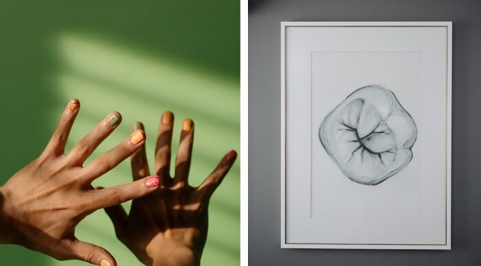 Hands with colorful nails casting shadows on a green wall next to framed abstract art.