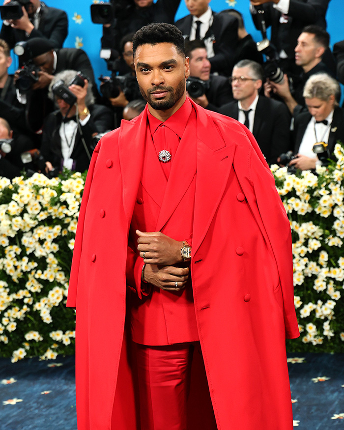 Regé-Jean Page in a striking red suit and overcoat, embodying celebrity fashion at the Met Gala.