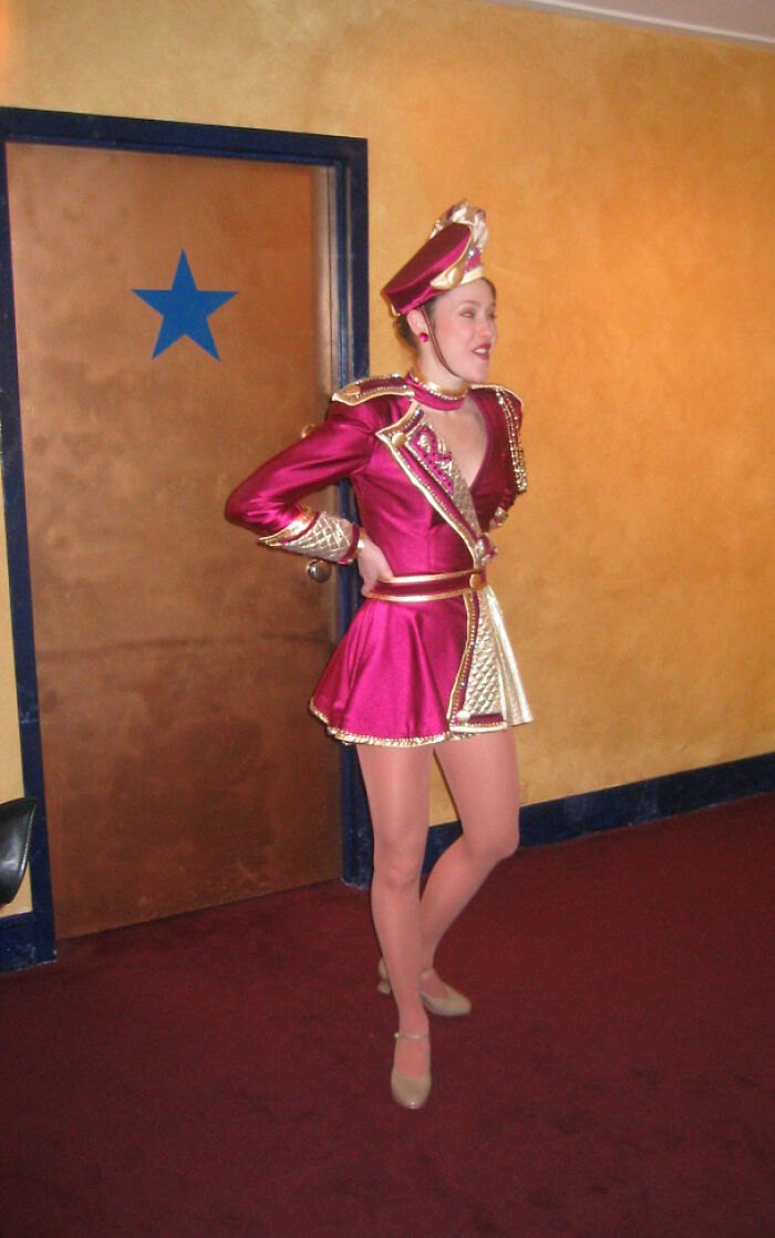 Young woman in maroon and gold costume posing indoors, illustrating inspiring and interesting stories about moms.