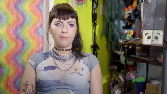 Woman with dark hair and tattoos sitting in colorful room explaining why she enjoys sploshing in the bedroom.
