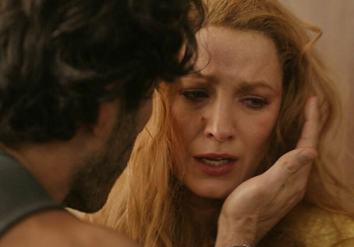 Close-up of a woman looking distressed as a man gently holds her face, capturing a tense emotional moment in a drama scene.