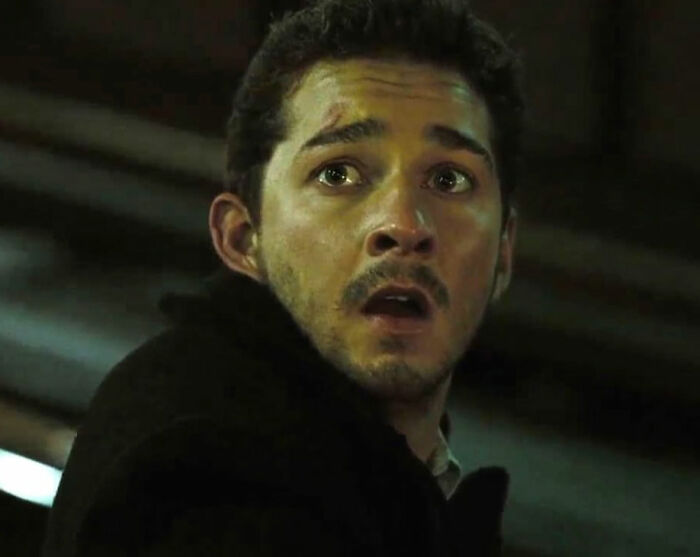 Shia LaBeouf looking shocked in a dimly lit scene, related to Bryan Cranston’s brutal and direct remarks.