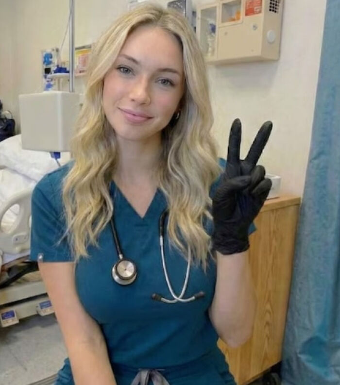Blonde woman in scrubs and stethoscope, making a peace sign. Is this the MAGA Influencer whose real identity was revealed?