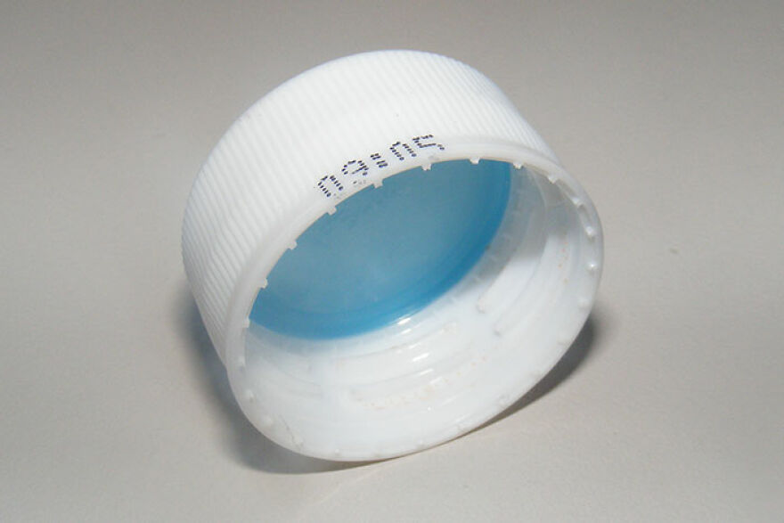 A white plastic bottle cap with a blue interior, lying on its side. This photo will take you down memory lane.