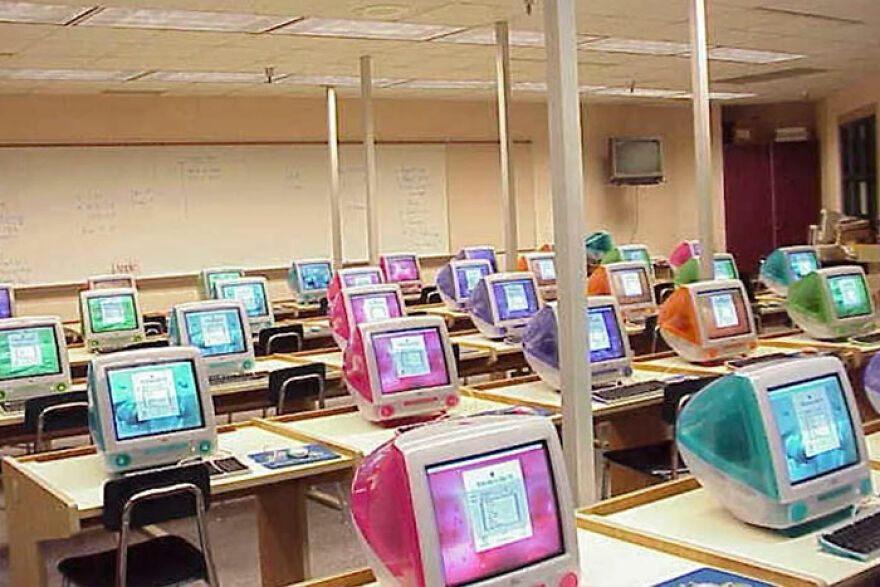 A classroom filled with rows of colorful, translucent iMac G3 computers, evoking a trip down memory lane.